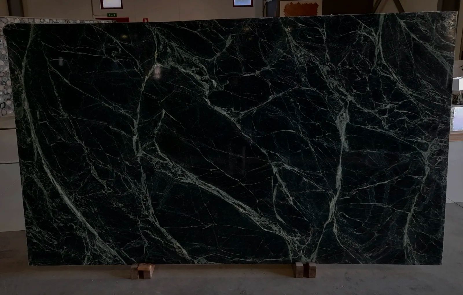 Una lastra di marmo scuro con venature chiare, sui cavalletti in magazzino